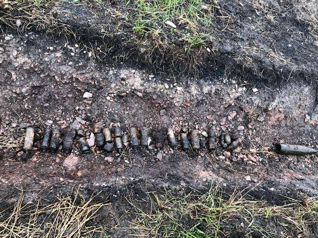 Birds eye view of a shallow excavated trench which contained a row of over a dozen buried WWII-era mortar rounds and a 25lb projectile which was discovered on a wind farm project in Scotland.