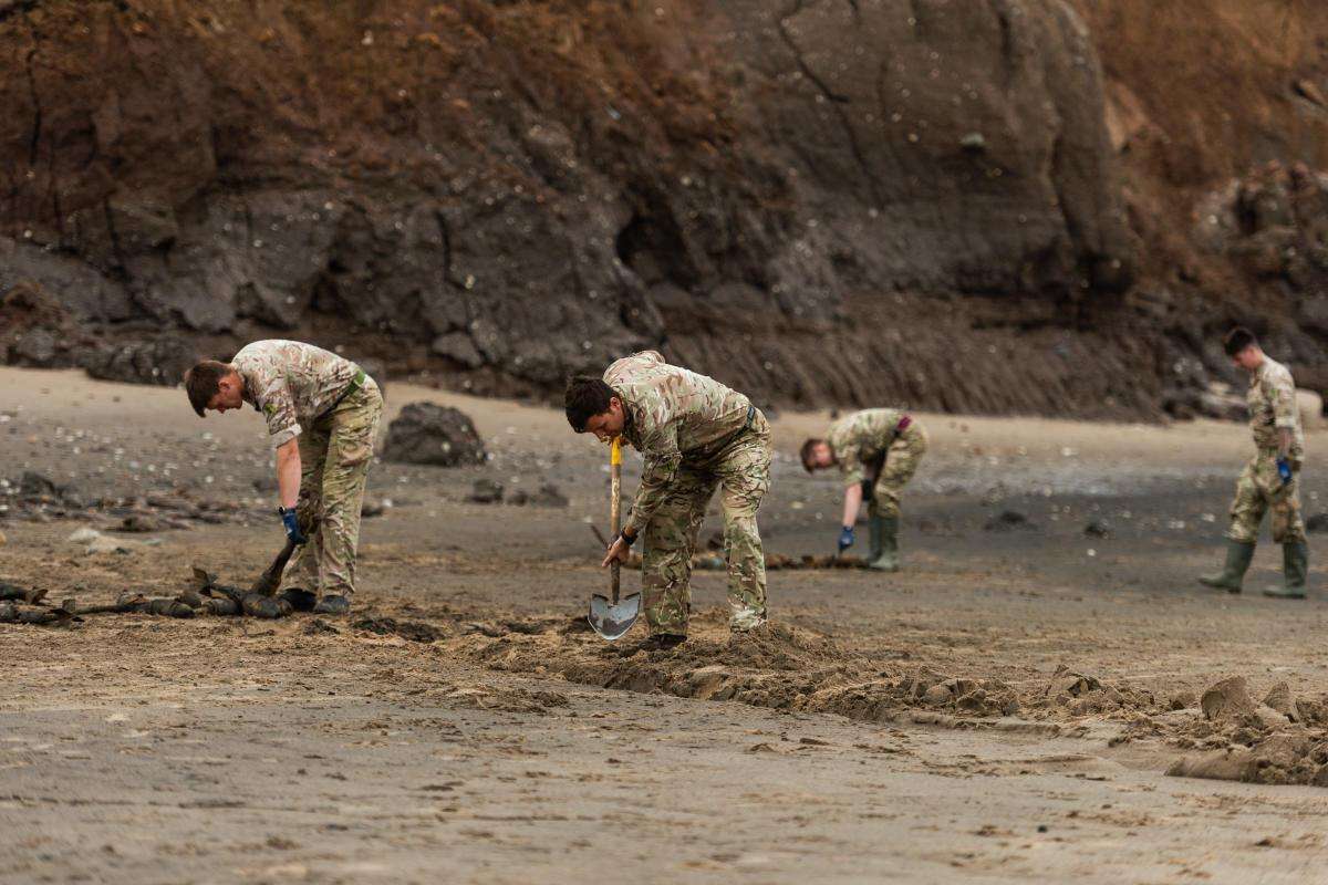 Four military personal digging a trench for clearing unexploded bombs from the beach at Cowden Sands in Yorkshire. Image source: Gazette & Herald