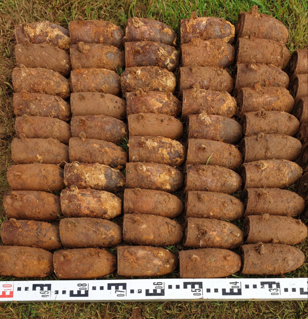 WWII Practice bombs laying on the ground against a large ruler