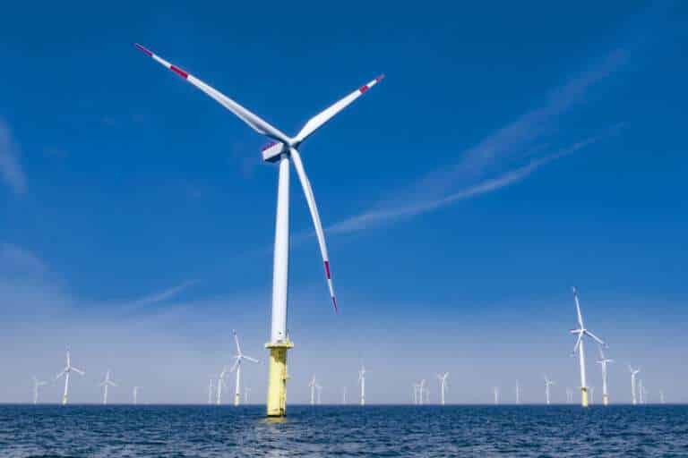 Offshore wind farm and the turbines spinning against blue sky